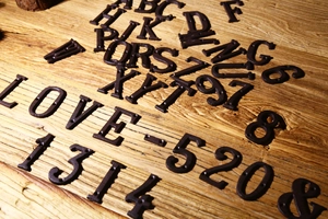 Lettere e numeri in ghisa retrò che formano LOVE 520 e 1314 su sfondo in legno naturale