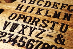 Lettere e numeri in ghisa vintage disposti su uno sfondo di legno rustico naturale