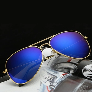 Detailed macro view of gold aviator sunglasses with blue gradient lenses on a magazine