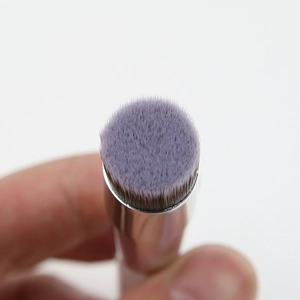Macro shot of purple bristles on a small flat-head concealer and foundation brush