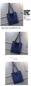 Vertical blue denim tote bag detail featuring double front pockets and washed canvas texture