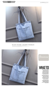 Close-up of light blue denim tote bag featuring dual front pockets and durable canvas texture