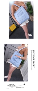 Detail shot of light blue denim tote bag with functional front pocket on a casual model
