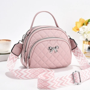 Quilted pink crossbody bag with triple zippers, metal bow, and woven shoulder strap