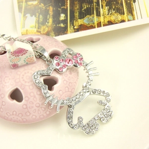 Detalle de un collar con colgante de gato de dibujos con diamantes blancos y rosas