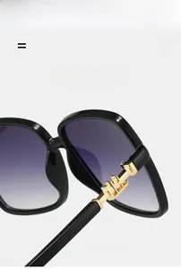 Detailed close-up of large square sunglasses with golden H hinges and gradient lenses