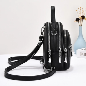 Detail view of black lychee leather backpack with triple silver zippers and adjustable strap