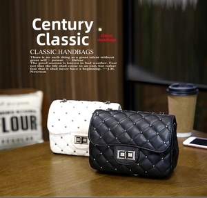 Close-up of quilted chain bags in black and white with silver studs on a wooden table
