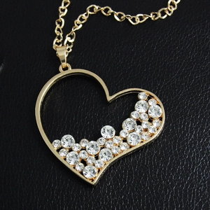 Collana dorata con ciondolo a cuore e cristalli bianchi scintillanti su sfondo in pelle nera