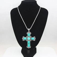 Detail of silver bohemian cross necklace with turquoise stones on a black neck bust