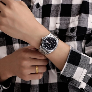 Montre KINGNUOS en acier argenté avec cadran noir, chiffres romains et affichage jour-date