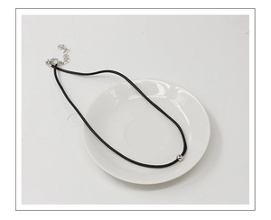 Détail du collier en cordon noir avec perle argentée et fermoir mousqueton sur plat