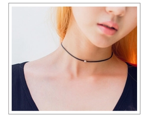 Gros plan d'un collier ras du cou en cordon noir avec une petite perle argentée