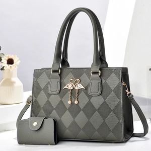 Détail du sac matelassé gris foncé avec pendentif cygne doré et bijou en perle