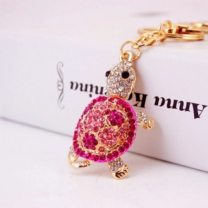 Sparkling pink rhinestone sea turtle keychain with gold alloy finish on a book background