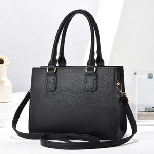 Detalle de bolso tote de cuero granulado negro con herrajes dorados y correa ajustable