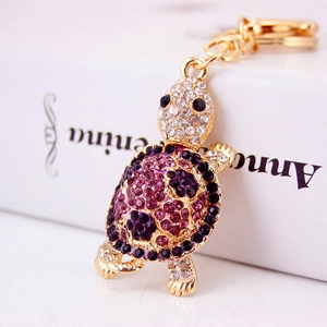Charming gold-plated turtle keychain with sparkling purple and white crystals for bags