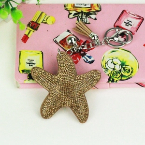 Macro detail of starfish keychain with golden rhinestones, tassel, and silver bell