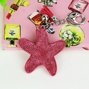 Macro shot of rose pink starfish bag charm with glittery rhinestones and red tassel