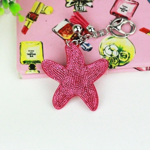 Close-up of pink starfish keychain with rhinestones, silk tassel and metal bell detail