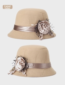 Détail d'un chapeau cloche en laine camel avec grande rose en tissu et voile résille