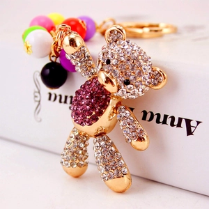 Cartoon gold bear keychain with purple crystals and colorful beads on a book
