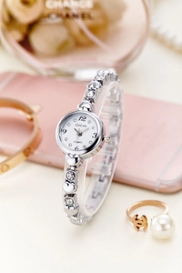 Detail of silver quartz watch with heart-shaped metal band and sparkling rhinestones