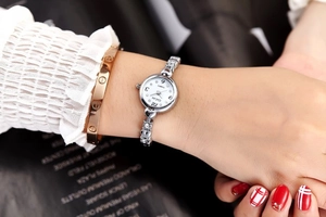 Close-up of women's silver quartz watch with heart-shaped rhinestone band on wrist