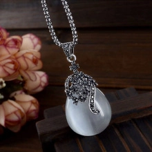 Detail of bohemian drop-shaped white opal pendant with antique silver floral carvings