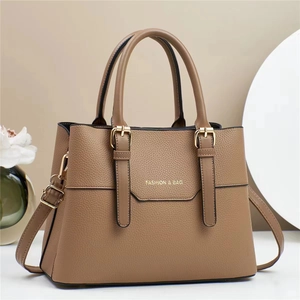 Brown leather women handbag with double handles and gold hardware in elegant studio setting