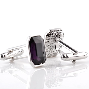 Close-up of polished silver cufflinks featuring emerald-cut deep purple crystal stones