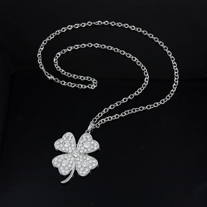 Macro shot of silver four-leaf clover necklace with sparkling crystals on black background