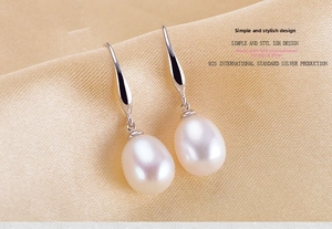 Macro shot of natural freshwater pearl earrings with S925 sterling silver hooks on silk
