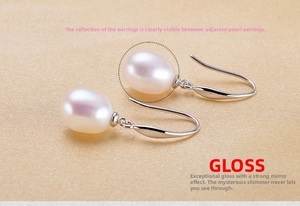 Close-up of S925 silver hook earrings with white teardrop pearls on silk background