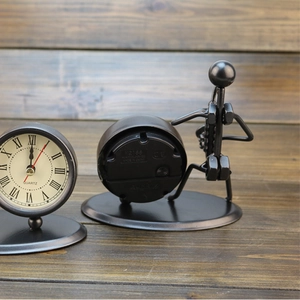 Vintage creative iron musician desk clock with Roman numeral dial on wooden background.