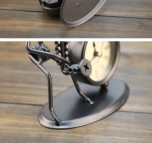 Detail of vintage industrial iron desk clock with metal figurine on wood table