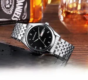 Montre homme en acier avec cadran noir et chiffres romains sur une table en bois brun