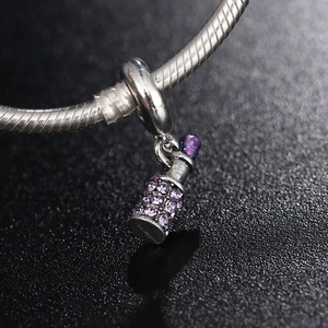 Macro view of silver bottle charm bead with purple crystals on snake chain bracelet
