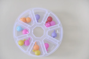Top-down view of clear circular plastic storage box with eight sections for colorful beads
