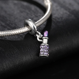 Macro view of silver lipstick charm with purple rhinestones on a snake chain bracelet