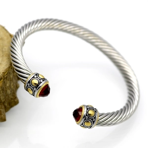 Detail of twisted cable cuff bracelet featuring silver wire and ruby-colored gemstones