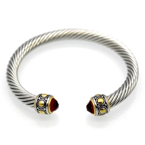 Silver twisted cable cuff bracelet with gold accents and red gemstones on white background