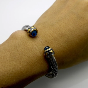 Detail of twisted cable open cuff bracelet with blue gemstones and gold accents