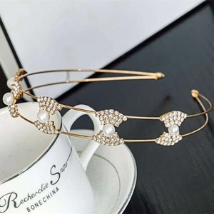 Close-up of golden metal headband with delicate pearls and rhinestones on a porcelain cup