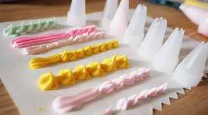 Detailed view of various piping tips creating colorful cream shapes for DIY crafts