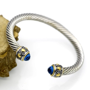 Close-up of cable twist silver bracelet with gold accents and blue faceted gemstones