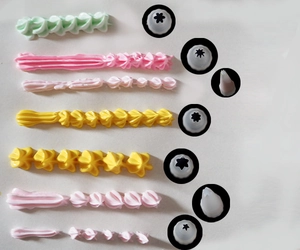 Close-up of various piping tips showing star and shell cream patterns in pastel colors