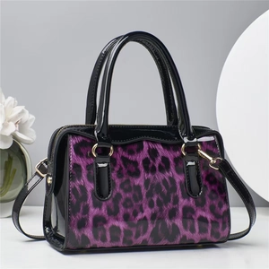Détail du motif léopard violet et des finitions en cuir noir brillant sur le sac à main