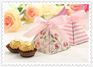 Detail of pyramid candy boxes with pink rose pattern and golden chocolate spheres