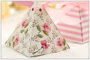 Close-up of small pink rose triangular gift box with silk ribbon for wedding candy